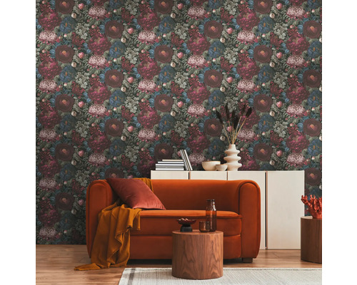 Woonkamer met bloemmotiefbehang, oranje bank en houten tafels op een tapijt