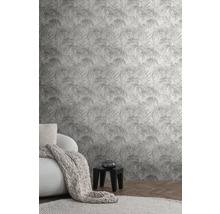 Woonkamer met palmpatroonbehang, fauteuil, deken en bijzettafel.