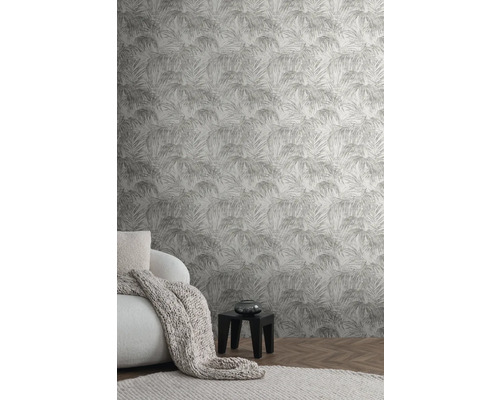 Woonkamer met palmpatroonbehang, fauteuil, deken en bijzettafel.