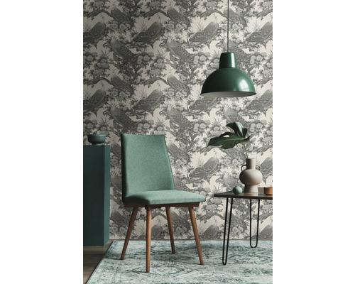 Woonkamer met behang met pauwenmotief, stoel, tafel en hanglamp