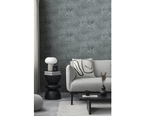 Woonkamer met grijs bladbehang, bank, tafel en decoraties voor een stijlvolle ambiance.