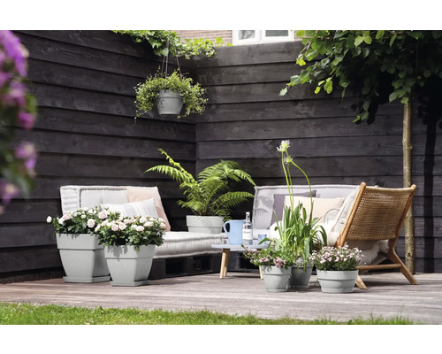 Terras met grijze plantenbakken, houten meubels en planten