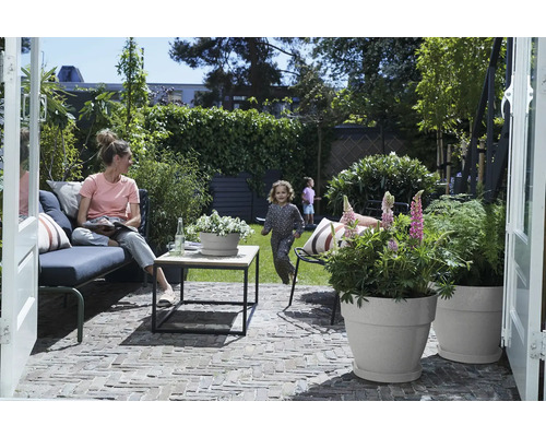 Tuinscène met vrouw op een bank, spelende kinderen en beplante bloempotten