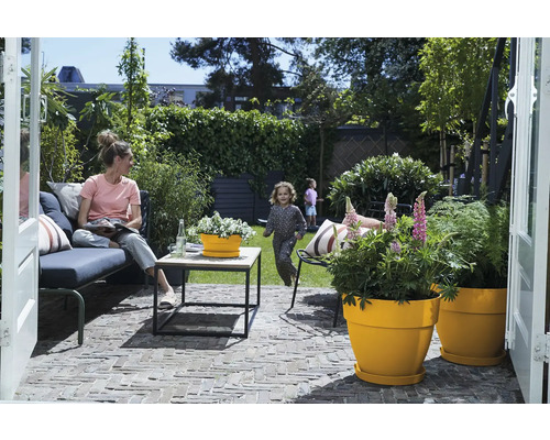 Terras met tuinmeubelen, plantenbakken en spelende kinderen op de achtergrond