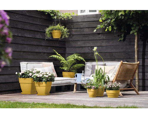 Gezellige tuinscène met planten in plantenbakken, zitmeubels en houten schutting