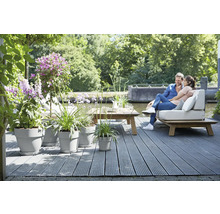 Licht terras met houten dek, beplante bloempotten en een stel op een bank