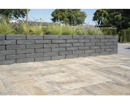 Muur van grijze stenen en bestrating in de tuin