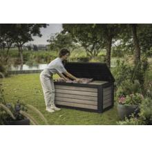 Een vrouw ruimt een tuinkist in de tuin in. De tuinkist is gemaakt van hout en kunststof.