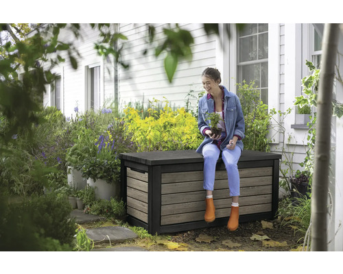 Vrouw zit op een weerbestendige opbergbox in de tuin