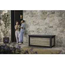 Tuinscene met opbergbox, stenen gevel en twee vrouwen