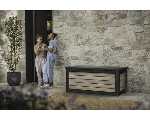 Tuinscene met opbergbox, stenen gevel en twee vrouwen