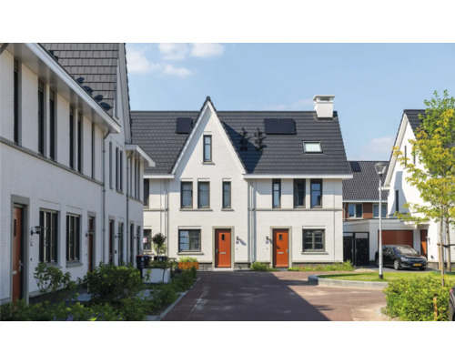 Aanzicht van een woonwijk met huizen met pannendaken en zonnepanelen.