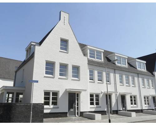 Meerdere witte rijtjeshuizen met dakramen onder een blauwe lucht.