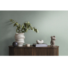 Decoratieve objecten op een houten kast, waaronder een vaas met takken, boeken en een sculptuur