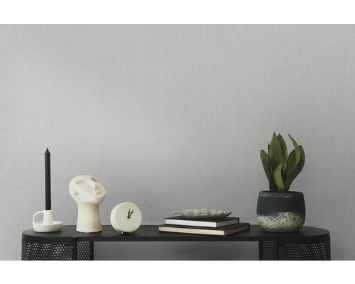 Decoratieve objecten zoals kandelaar, sculptuur, klok, boeken en kamerplant op een zwarte plank voor een gestructureerde wand.