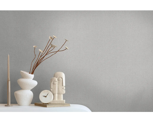 Close-up van een grijs behang met decoratieve elementen zoals een vaas, een sculptuur en een klok