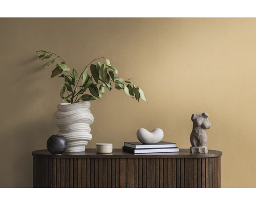 Decoratieve scène op een donkerhouten kast met een witte vaas, groene bladeren, boeken en beelden.