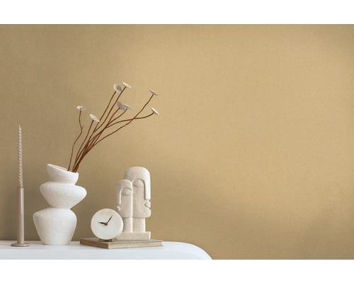 Decoratieve scène met een vaas, takken, een kaars, een klok en een sculptuur op een tafel.