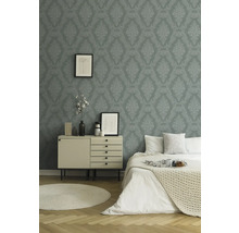 Slaapkamer met patroonbehang, commode, bed en rond vloerkleed
