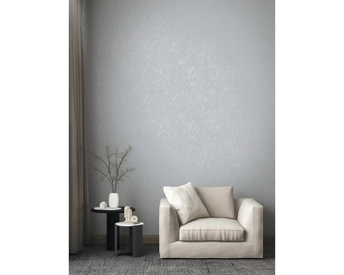 Lichte woonkamer met bloemenbehang, fauteuil en bijzettafels.