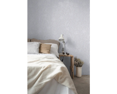 Slaapkamer met bed, nachtkastje, lamp en behang met plantmotief