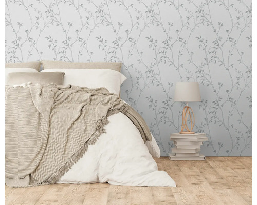 Slaapkamer met bed, nachtkastlamp en behang met plantenpatroon