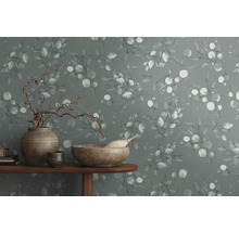 Decoratieve muur met eucalyptuspatroon en woonaccessoires op een tafel.