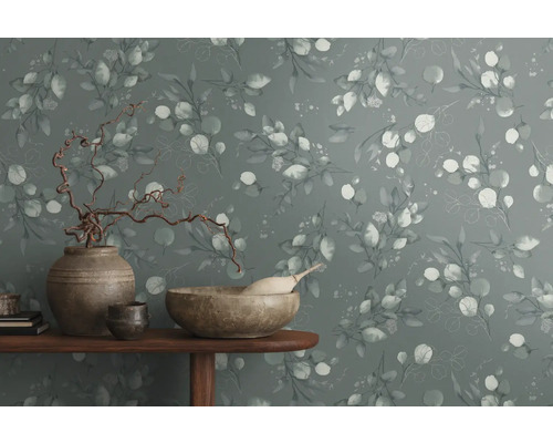 Decoratieve muur met eucalyptuspatroon en woonaccessoires op een tafel.