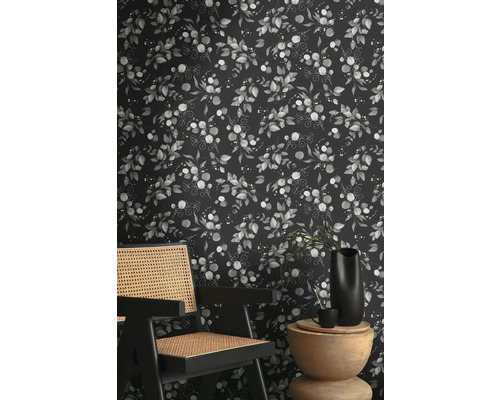 Kamerzicht met een behang met eucalyptusplantenpatroon achter een houten stoel en bijzettafel.