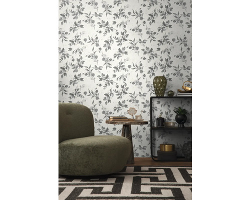 Gedecoreerde woonkamer met een behang met eucalyptusplantenpatroon, een fauteuil, een tafel en een plank.
