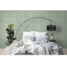Slaapkamer met bed voor een groen behang met bloemmotief