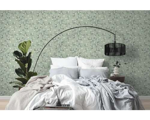 Slaapkamer met bed voor een groen behang met bloemmotief