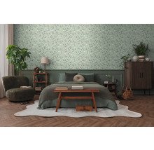 Slaapkamer met bed, fauteuil, dressoir en bloemenbehang.