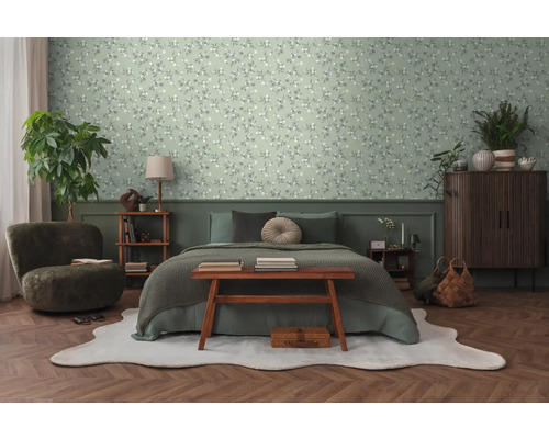 Slaapkamer met bed, fauteuil, dressoir en bloemenbehang.