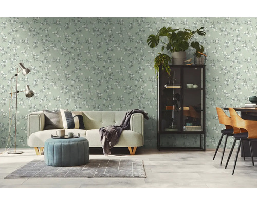 Lichte woonkamer met een bank, een fauteuil en een patroonbehang.