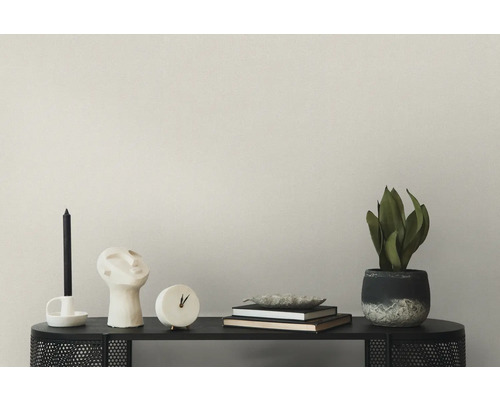 Decoratief stilleven op een zwarte plank met kaars, sculptuur, klok, boeken en potplant.