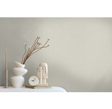 Decoratieve opstelling met kaars, vaas met planten, klok en sculptuur op een tafel.