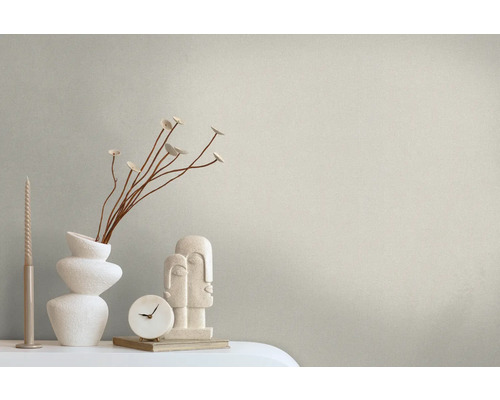 Decoratieve opstelling met kaars, vaas met planten, klok en sculptuur op een tafel.