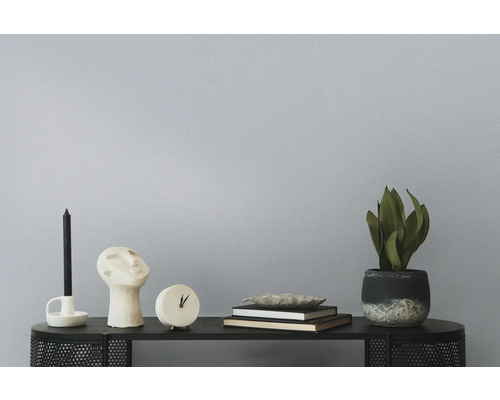 Decoratieve objecten op een plank, waaronder een kaars, een buste, een klok, boeken, een schaal en een kamerplant.