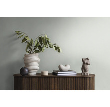 Decoratieve opstelling met vaas, sculpturen en boeken op een houten kast.
