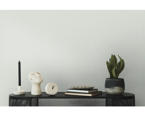 Decoratieve scène met kaars, beeld, klok, boeken en potplant op een zwarte tafel