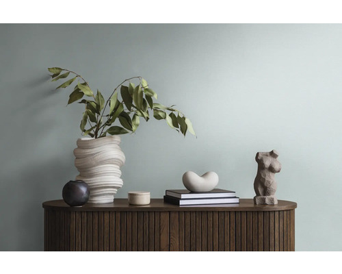 Decoratieve opstelling op een houten kast met vaas, plant, boeken en sculpturen.