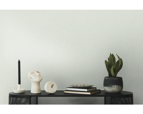 Decoratieve opstelling op een zwarte tafel met kaars, sculptuur, klok, boeken en kamerplant