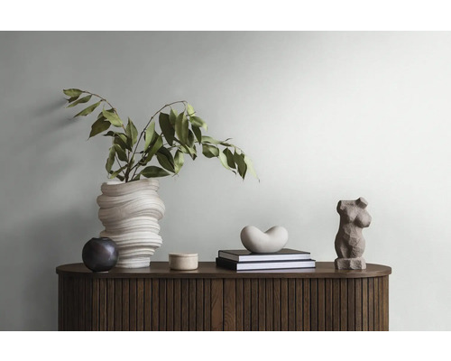 Decoratief interieur met houten dressoir, vaas met groene plant, boeken en sculpturen.