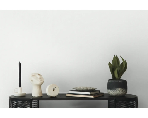 Decoratieve scène op een zwarte tafel met kaars, sculptuur, klok, boeken en een kamerplant