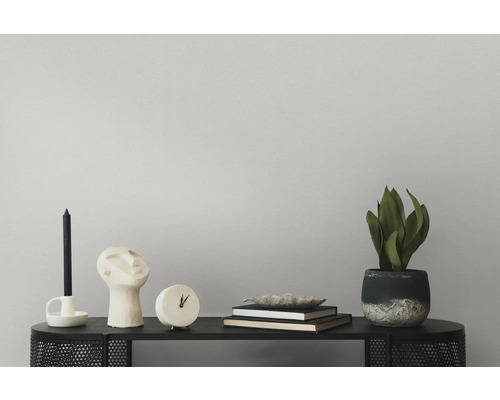 Decoratieve opstelling met kaars, beeld, klok, boeken en kamerplant op een zwarte tafel