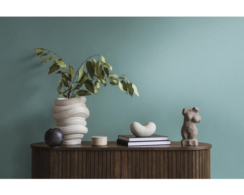 Decoratieve opstelling met een vaas, boeken en een figuur op een houten kast.