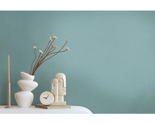 Decoratieve scène met vaas, gedroogde bloemen, kaars, klok en sculptuur op een tafel.