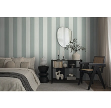 Slaapkamer met bed, bijzettafel, rek en stoel voor een gestreept wandbehang