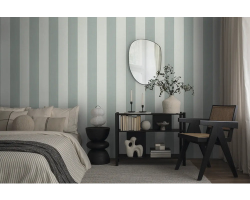 Slaapkamer met bed, bijzettafel, rek en stoel voor een gestreept wandbehang